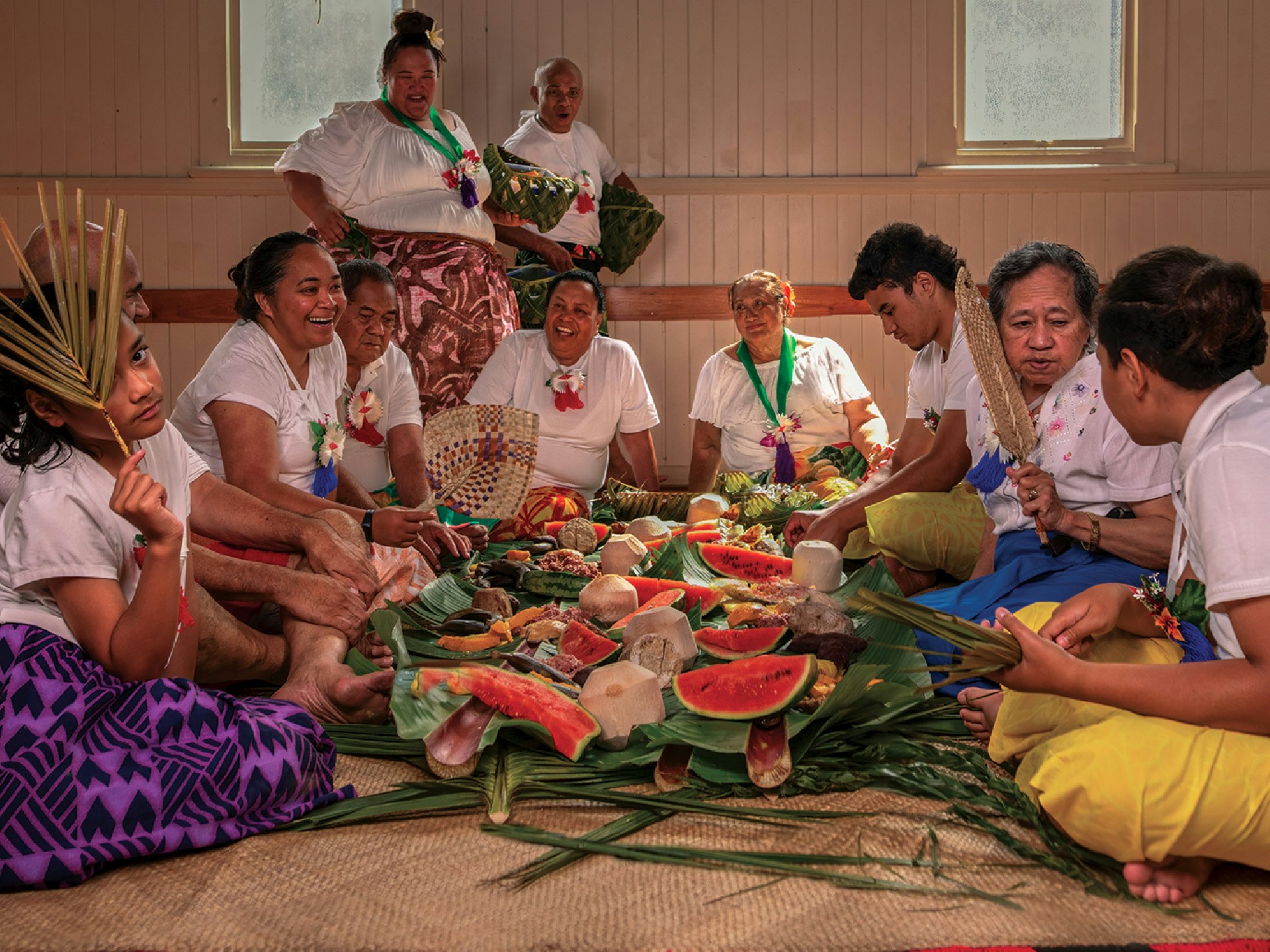Rotuma Language Week story tile. Photo from Ministry of Pacific Peoples People sitting around a feast on a woven mat.