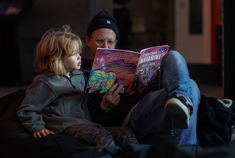 An adult is reading a book about Matariki to a child.