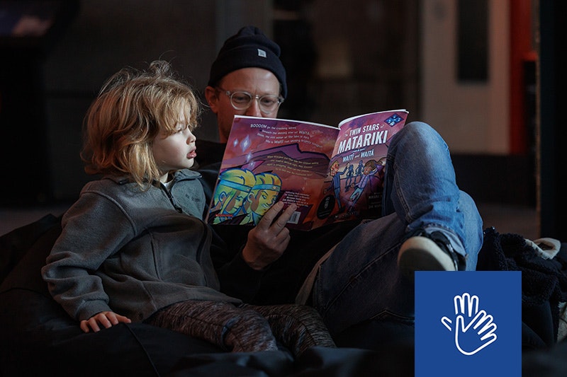 An adult is reading a book about Matariki to a child.