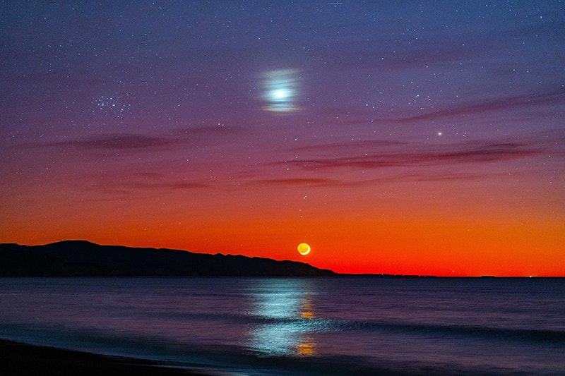 A sun at sunrise, with a blurry moon.