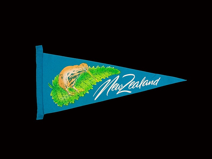 Souvenir pennant, 'New Zealand', Unknown; manufacturer(s); 1970s-1980s; New Zealand. Gift of Alan Tennyson, 2009. Te Papa (GH020755) A blue triangular pennant felt flag with the words New Zealand on it, and a kiwi on top of a fern.