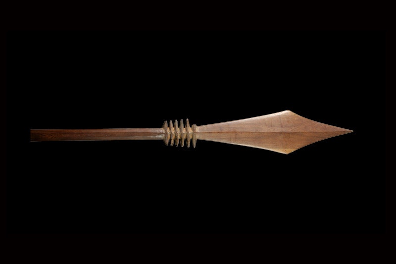 A wooden oar with a diamond-shaped paddle pointing right.