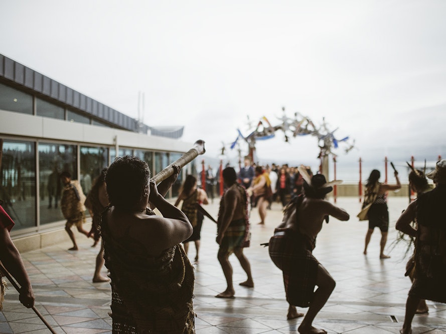 Opening pōwhiri for Ko Rongowhakaata: The Story of Light and Shadow, 2017. Photo by Tim Onnes. Te Papa Silhouettes of people in Māori clothing challenging people who are walking onto the marae atea at a pōwhiri.