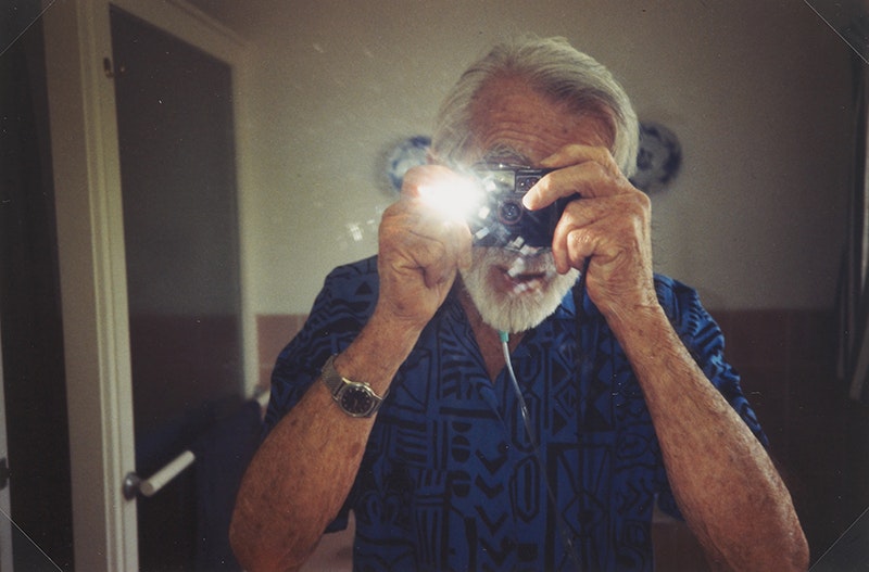 A man is taking a photograph of himself in a mirror and the flash has gone off.
