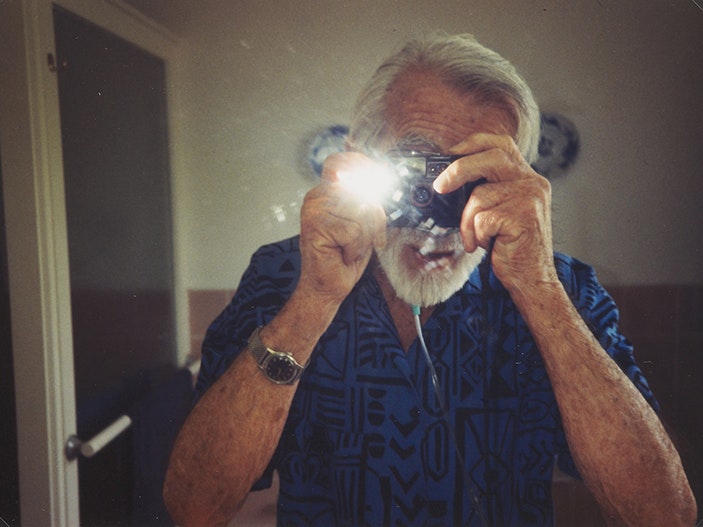 Self-portrait, the artist's last photograph, May 1993, Howick, by Eric Lee-Johnson. Purchased 1997 with New Zealand Lottery Grants Board funds. © Te Papa. CC BY-NC-ND 4.0. Te Papa (O.006062) A man is taking a photograph of himself in a mirror and the flash has gone off.