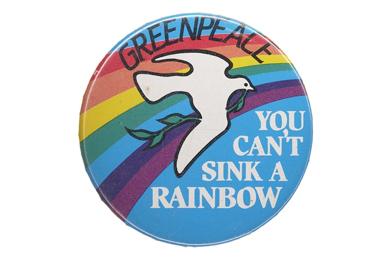 A badge with a dove on a rainbow with the words "Greenpeace. You can't sink a rainbow"