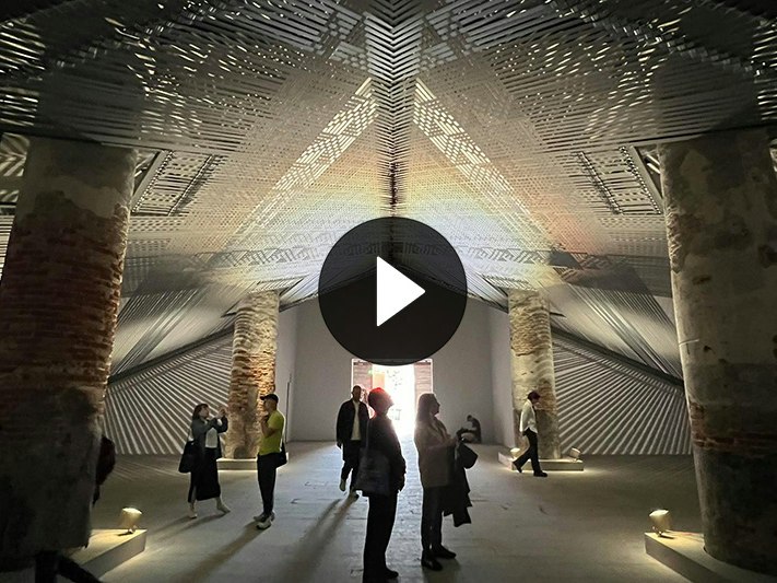 Mataaho Collective, Takapau on display at the Venice Biennale 2024. Photo courtesy of Mataaho Collective People standing in a large gallery with a weaving installation above them.