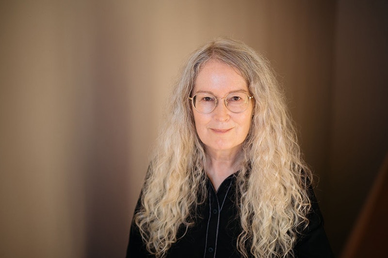 A woman with long white blonde hair is smiling at the camera.