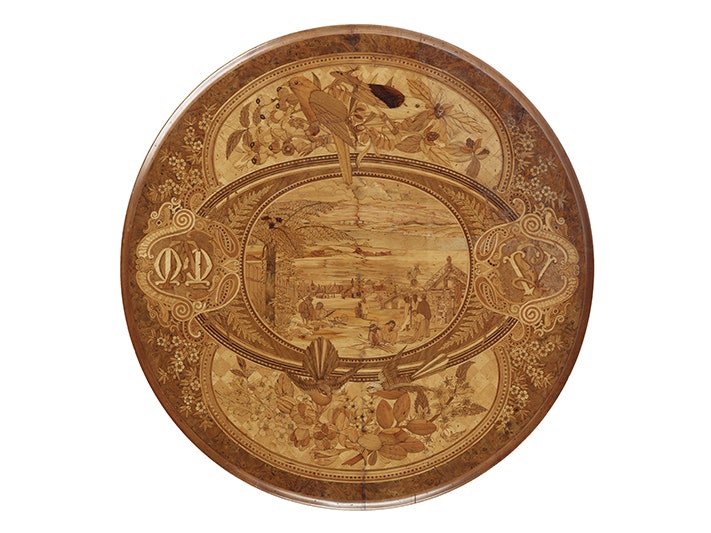 Table, with marquetry work top., circa 1880, New Zealand, by William Seuffert. Purchased 2011. CC BY-NC-ND 4.0. Te Papa (GH021400) A wooden tabletop with nature and people scenes inlaid onto it.