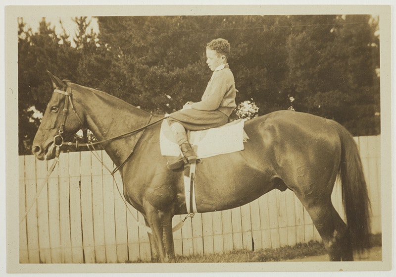 A sepia photo of a child is sitting on top of a horse.