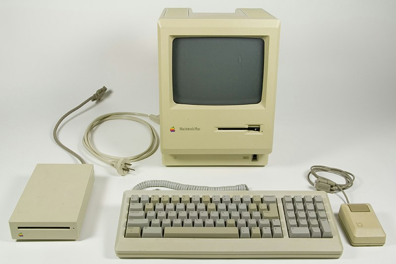 An old beige Macintosh computer monitor, keyboard, disc drive, and mouse.