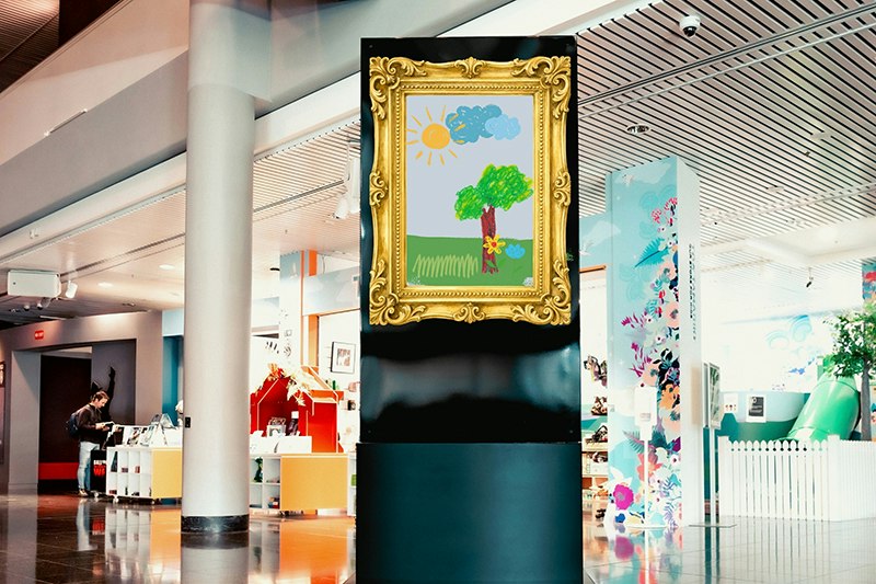 A photo of a framed child's painting in a large foyer space.