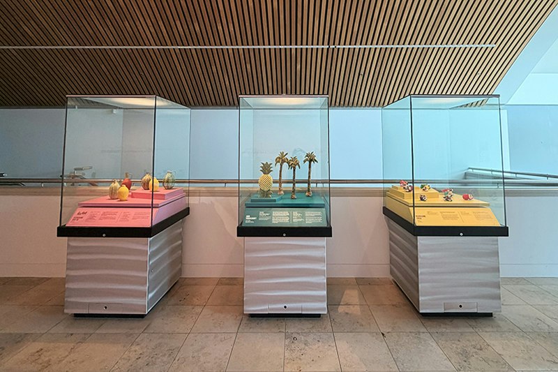 Three cases on a stone floor with ceramic artworks in them.